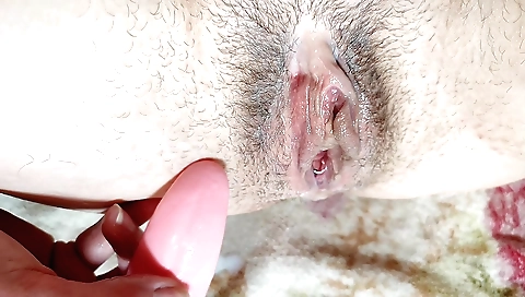 Hairy babe is playing with a vibrator in the bedroom